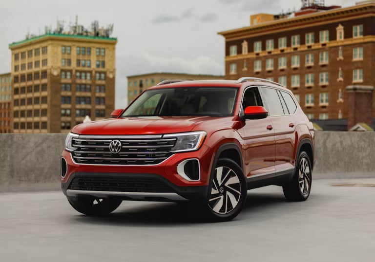 Red Volkswagen Atlas SUV parked in front of buildings.